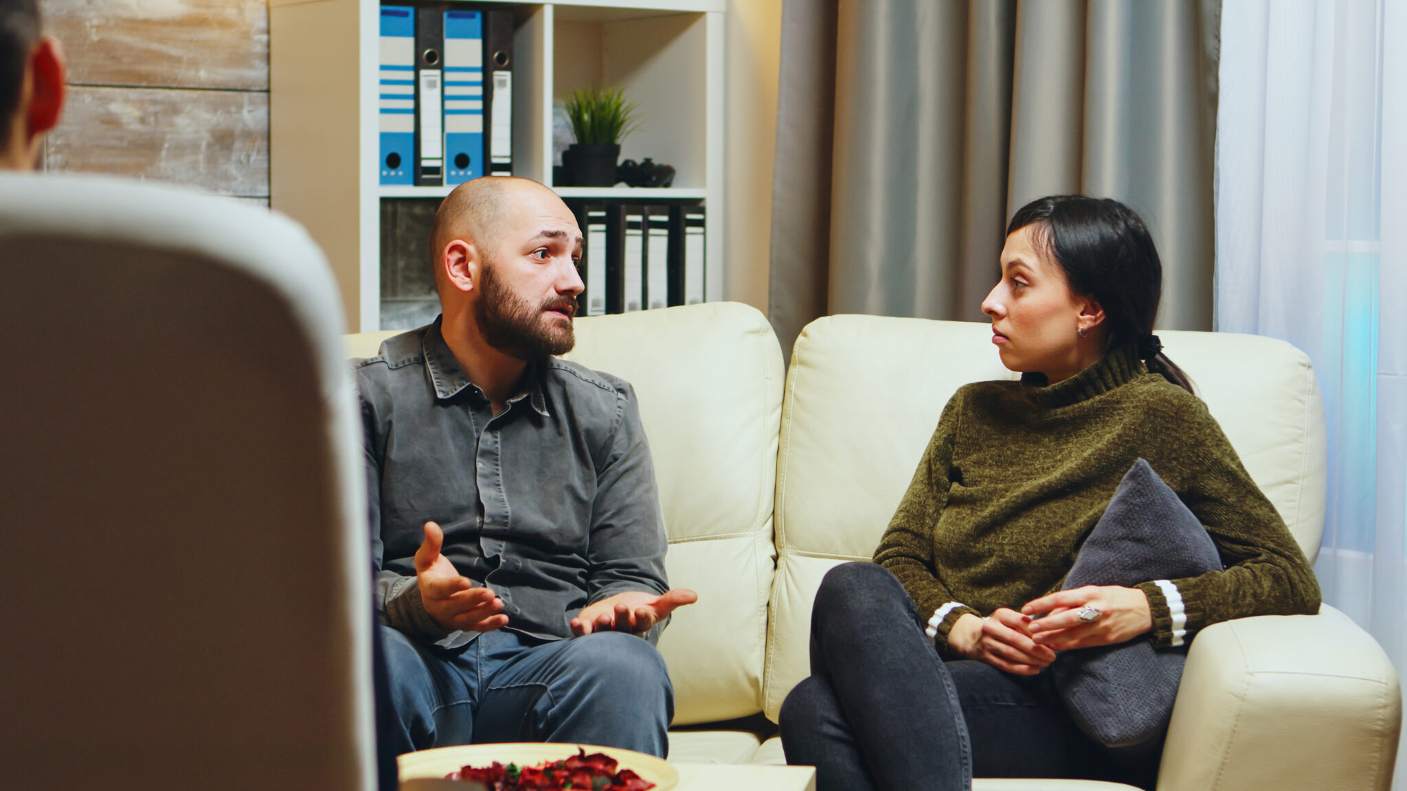 Young man telling his wife in front of therapist about what makes him unhappy regarding their relationship.